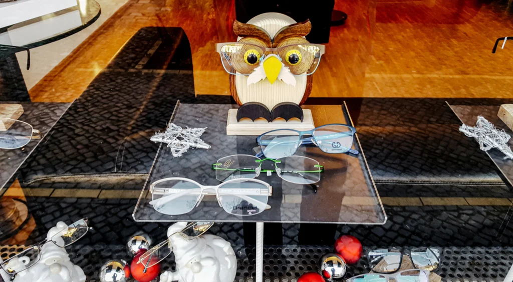 Augen-aufsetzen-Brillen-im-Schaufenster-mit-gebastelter-Eule-im-Hintergrund